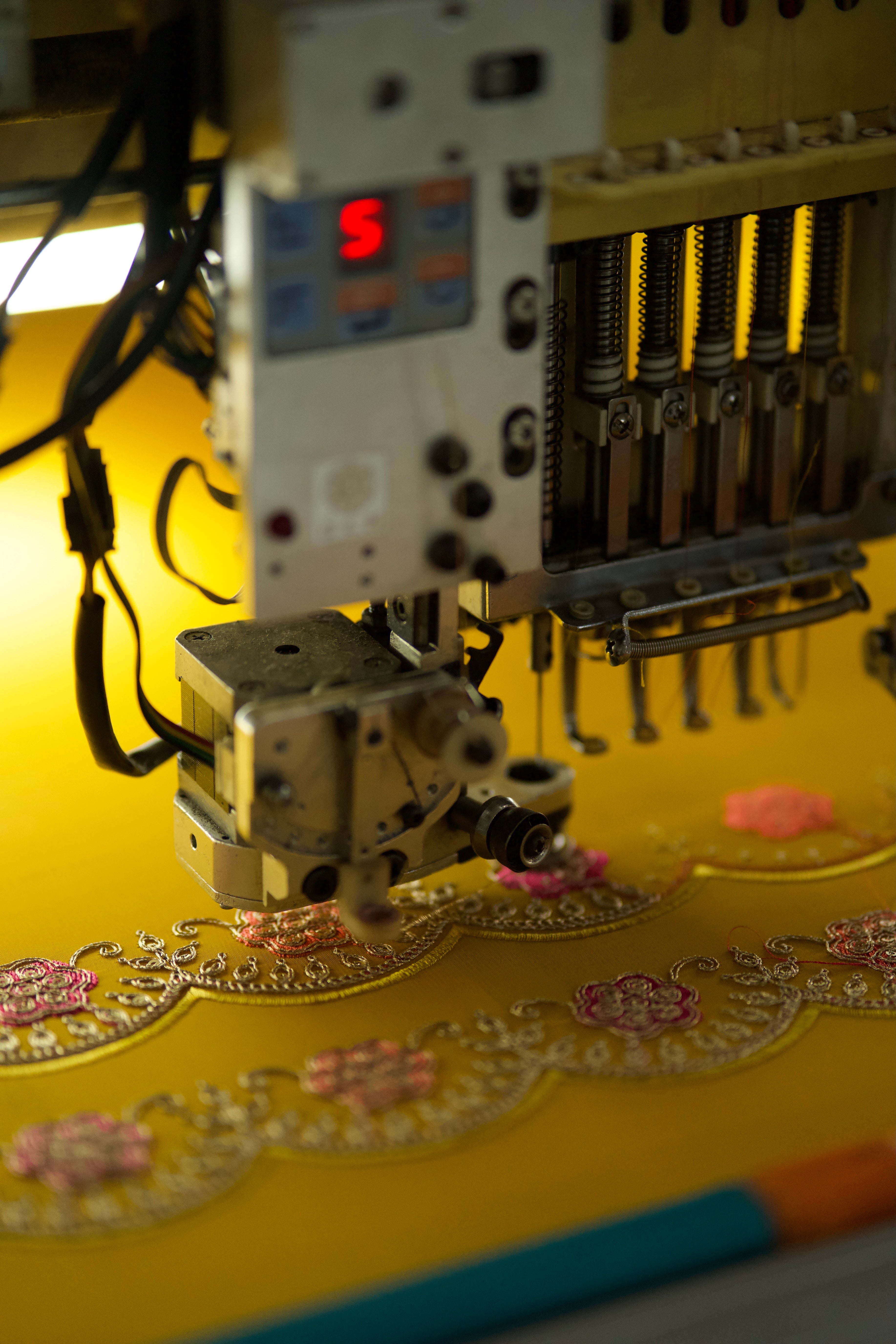 Embroidery machine in action on a yellow fabric with floral patterns.
